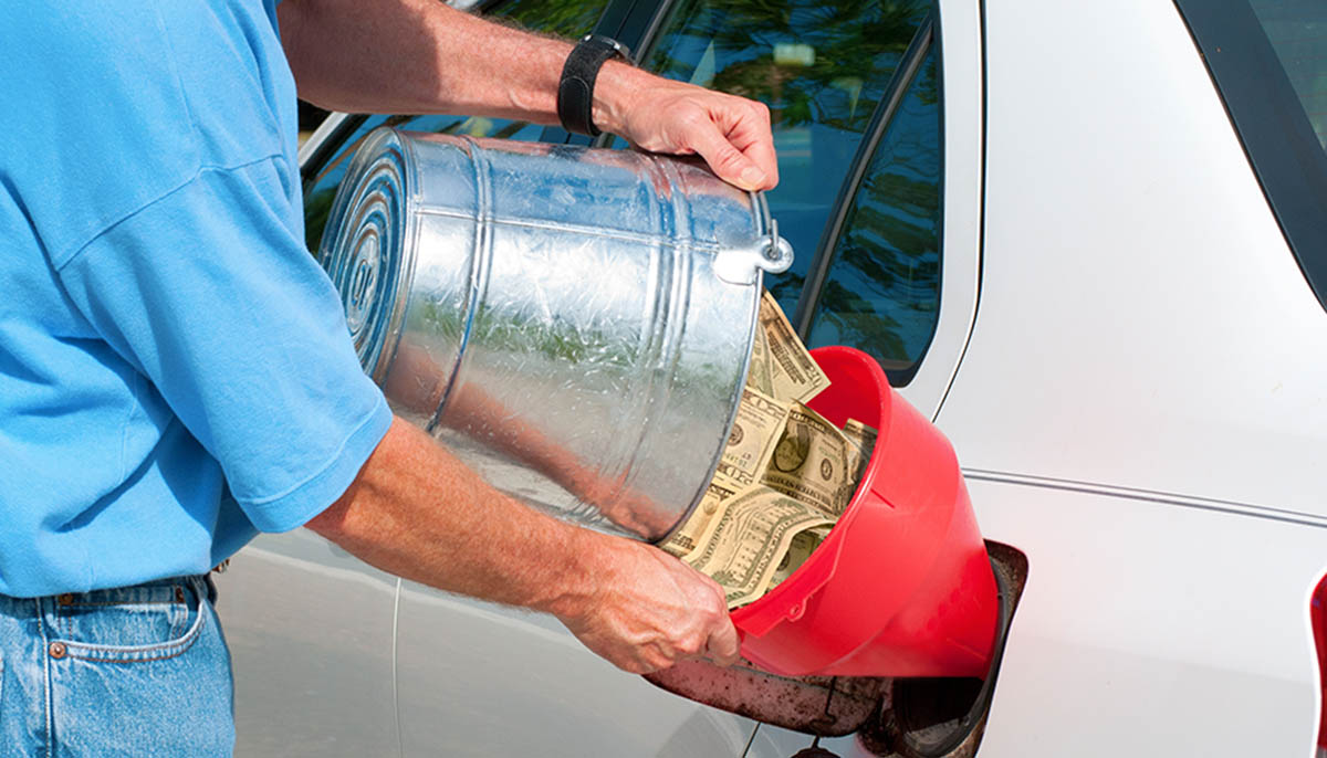 man funneling cash into his gas tank