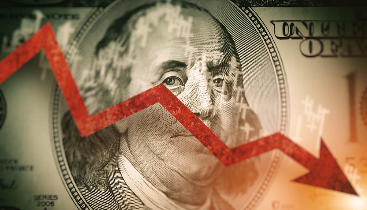 Closeup detail of dollar bill. Economist forecast for the United States. Glowing red arrow going downwards on Benjamin Franklin portrait on dollar bill. Effect of recession on US economy.