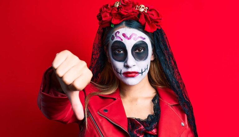 Woman wearing day of the dead costume over red looking unhappy and angry showing rejection and negative with thumbs down gesture. bad expression.
