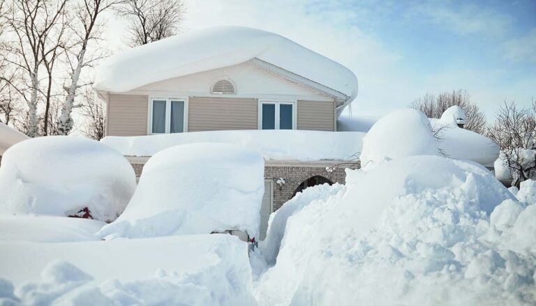 A house, roof and cars are covered with deep white snow in western new york for a weather or blizzard concept.