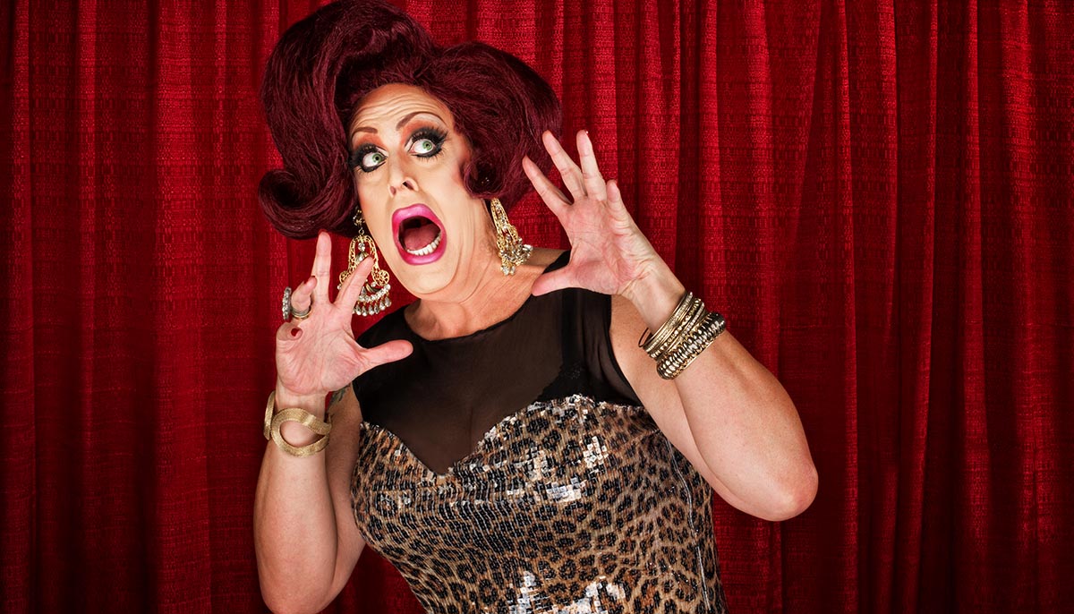 Scared drag queen with hands up in theater